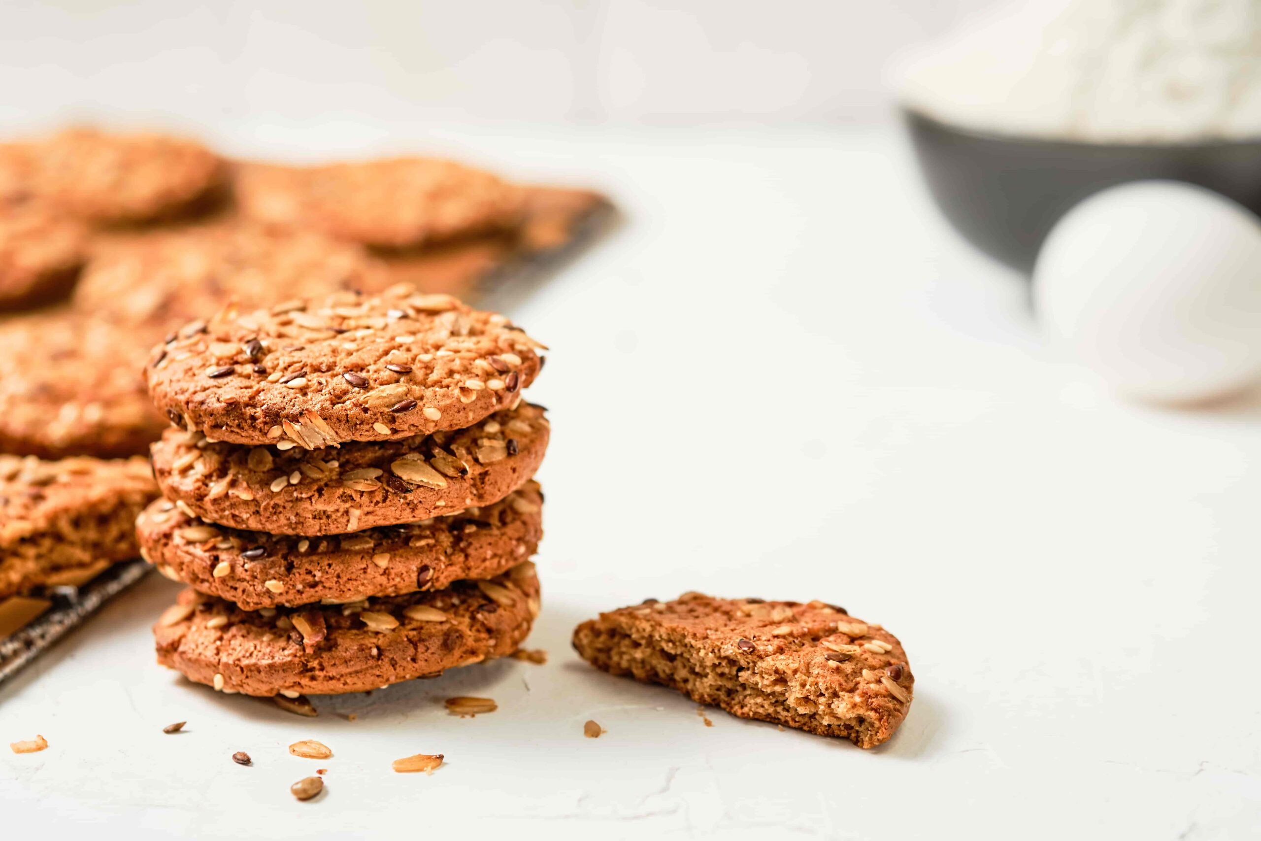 Oatmeal cookies with flax and sesame seeds on a white background. Eggs, flour - ingredients for making cookies, baking recipe. Selective focus on baked cookies, healthy breakfast. Festive baked goods